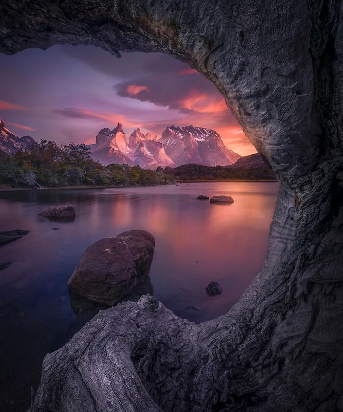 Framed rugged mountain peaks at sunset over a calm lake with trees, showcasing the best nature photography.