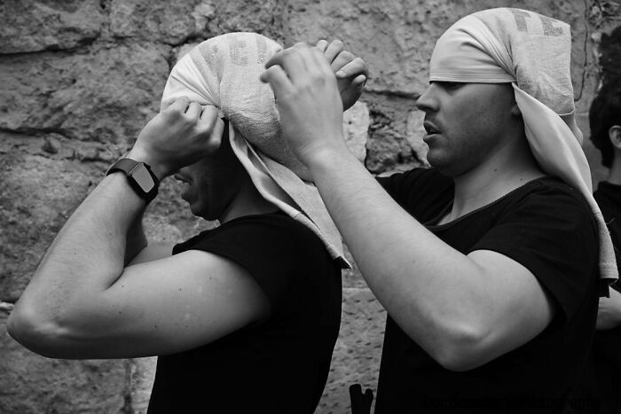 Two men in black shirts adjusting headscarves, capturing street moments that feel like magic in daily life.