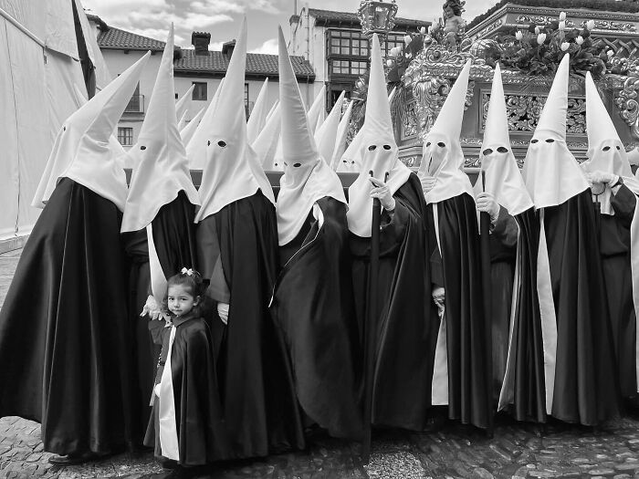Group of people in traditional pointed hoods and robes during a street moment capturing the marvels of daily life.