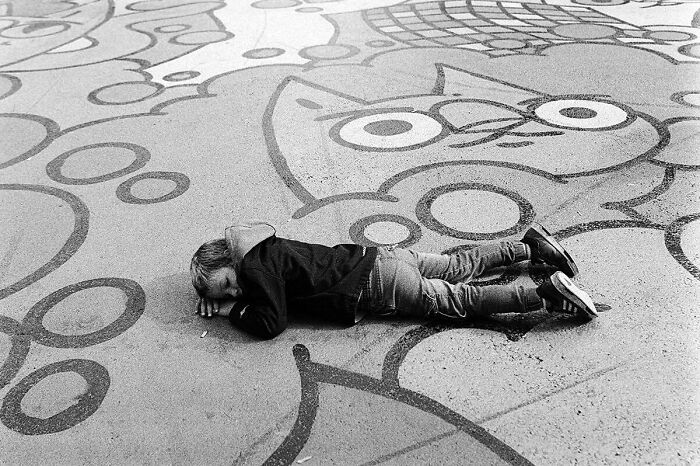 Child lying on a patterned street, capturing the marvels of daily life in magical street moments.