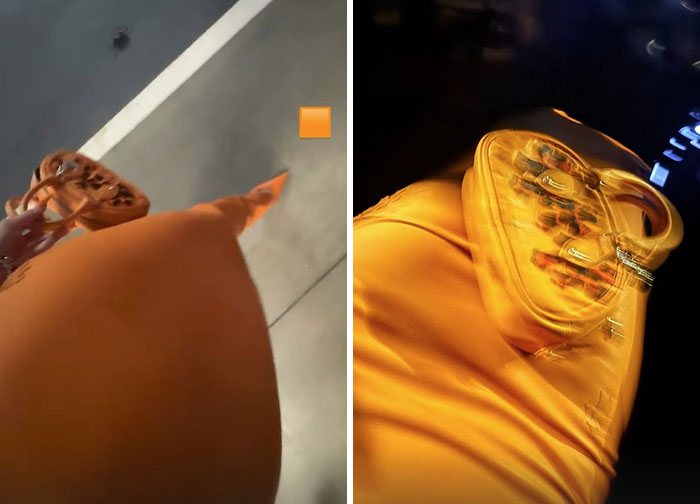 Woman wearing an orange dress and matching high heels, holding a designer handbag in a dimly lit setting