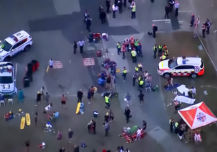 Aerial view of emergency responders and crowd at Bondi Beach after woman takes bullet for 3-year-old during attack. Aerial view of emergency responders and crowd at Bondi Beach after woman takes bullet for 3-year-old during attack.