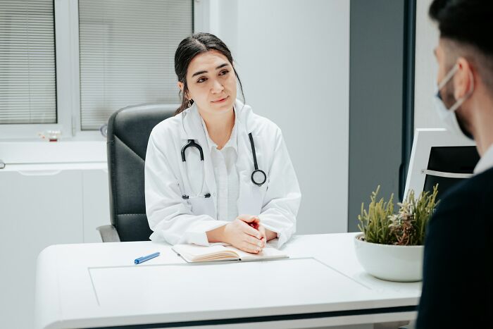 Female doctor with stethoscope consulting patient in office, discussing everyday things dangerous for health awareness.