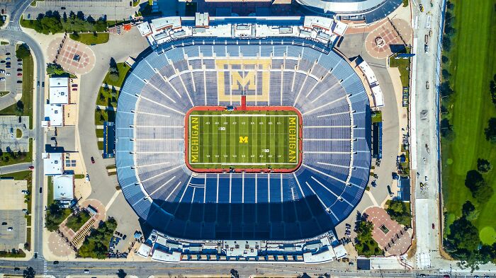 Aerial view of a large Michigan football stadium, symbolizing someone still stuck in their high school era years later.