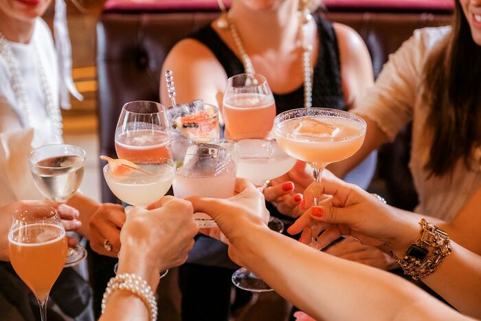 Group of friends raising cocktail glasses together highlighting harmless but toxic habits in social settings.