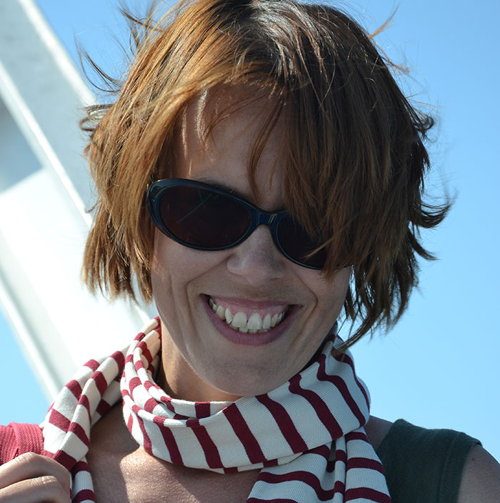 Smiling woman wearing sunglasses and striped scarf experiencing culture shocks after moving to Florida from Canada