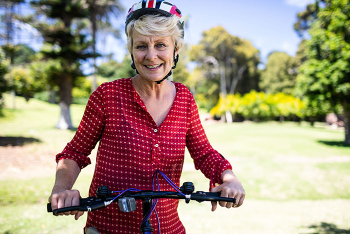 Woman wearing a helmet and red shirt riding a bike outdoors, illustrating culture shock after moving to Florida from Canada