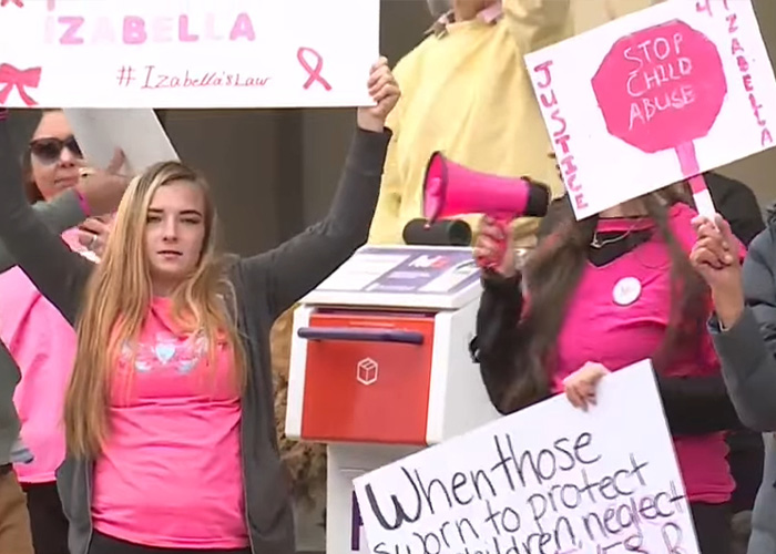 Protesters holding signs advocating justice and child a***e prevention in response to mom's chilling Google searches case.