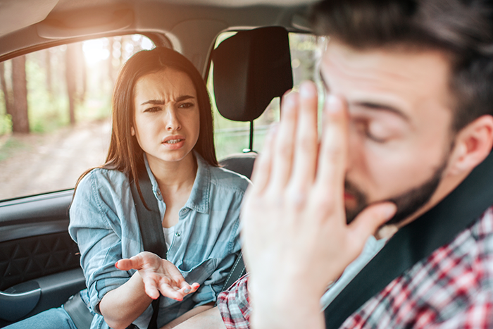 Couple arguing in a car, showing frustration and embarrassment, capturing a moment of tension and hunger conflict.