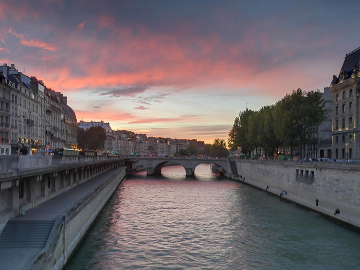 River view at sunset with a historic bridge and buildings, illustrating chaotic good moments in everyday life.