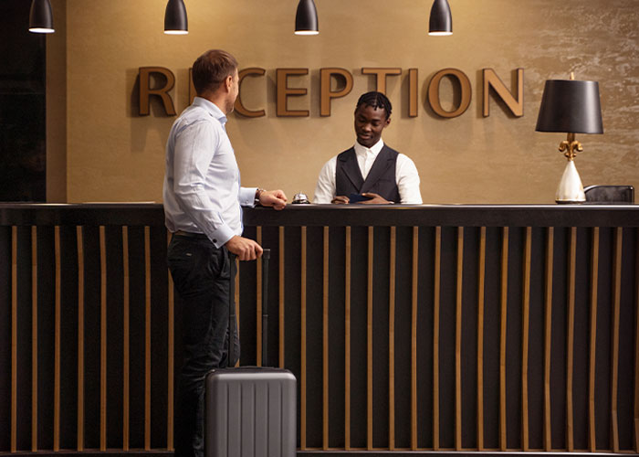 Hotel receptionist interacting with guest at the counter, revealing industry secrets customers rarely know.