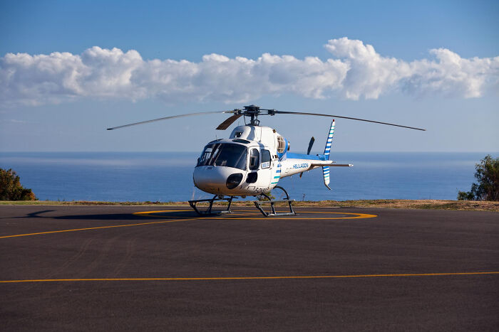Helicopter parked on asphalt near ocean, symbolizing the biggest bullet dodged without realizing at the time.