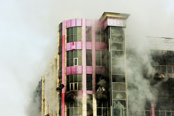 Smoke billows from a high-rise building with visible fire damage, illustrating the biggest bullet dodged in a disaster event.