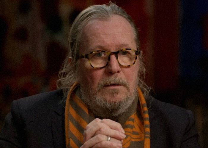 Hombre con gafas y barba en entrevista, ilustrando momentos de traición y backstabbing en Hollywood.