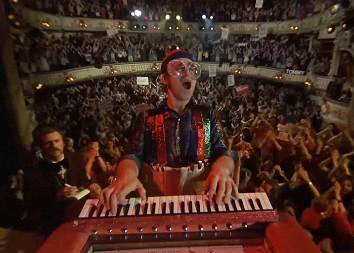 Hombre tocando teclado en concierto lleno de público, ilustrando momentos de traición y backstabbing en Hollywood.