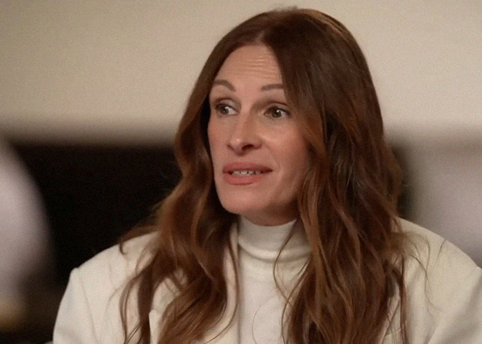 Actress with long brown hair wearing a white turtleneck, captured in a dramatic Hollywood backstabbing moment scene.
