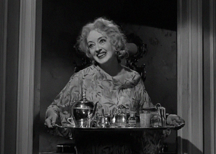 Actriz clásica en blanco y negro sosteniendo una bandeja con bebidas, ilustrando momentos de traición en Hollywood.