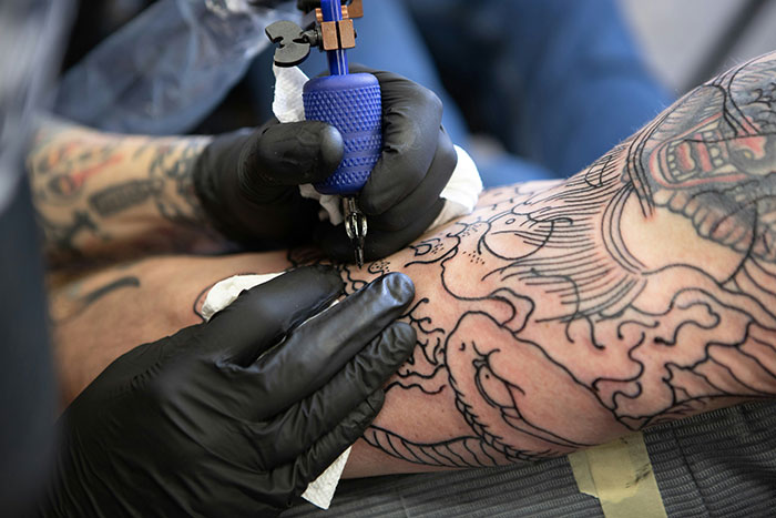 Close-up of a tattoo artist working on detailed arm tattoo symbolizing deepest secrets people refuse to reveal to their parents.