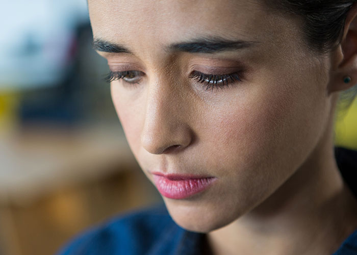 Close-up of a woman looking down thoughtfully, reflecting on engagement and fianc&eacute;&rsquo;s lie about her family.