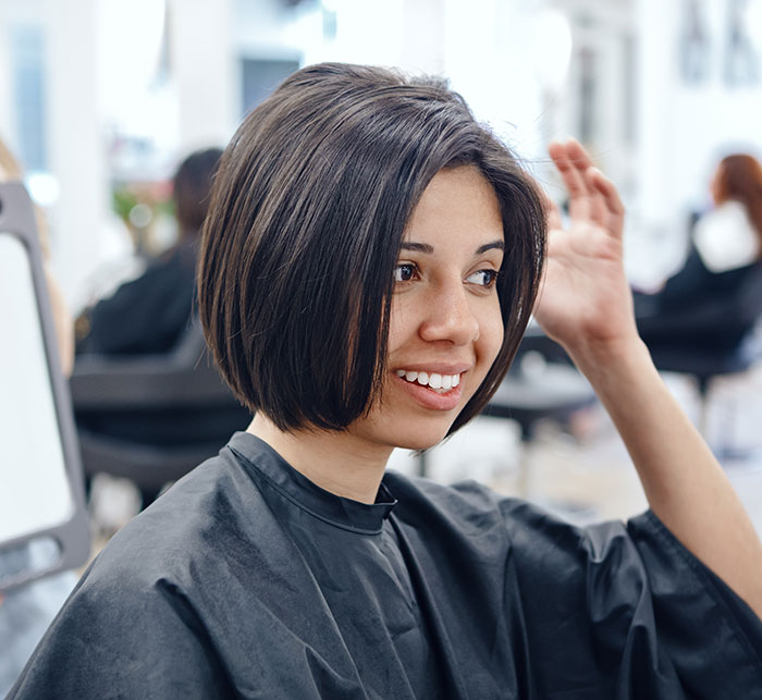 Young woman with a new hairstyle smiling in a salon representing Gen Z redefining rude Millennial women trends. Young woman with a new hairstyle smiling in a salon representing Gen Z redefining rude Millennial women trends.