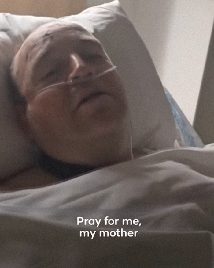 Man lying in hospital bed with nasal oxygen tube, appearing weak after Bondi Beach hero's hospital visit update.