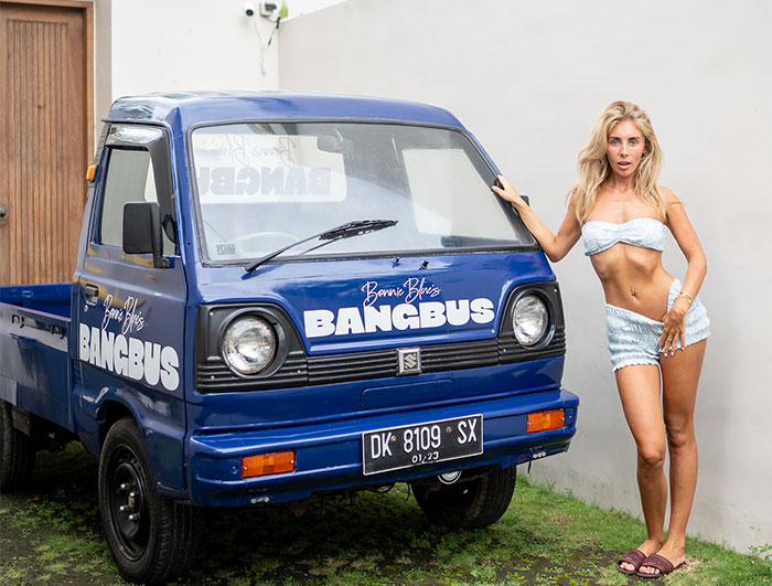 Bonnie Blue posing next to a blue Bangbus vehicle conveying a defiant message amid jail time threats.