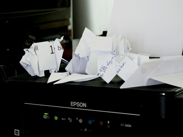 Crumpled and folded paper mess on a printer illustrating small design mistakes causing frustration.