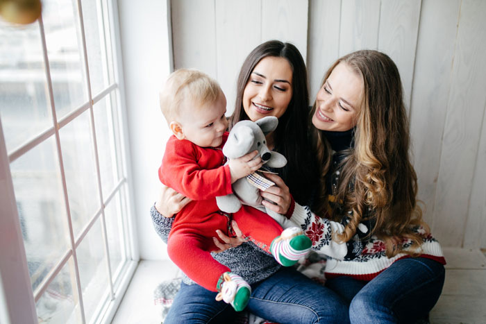 Two women and a baby by a window, illustrating family drama and custody court involving brother who abandoned his kid.
