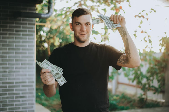 Young man outdoors holding cash in both hands, brother-money-wife-family