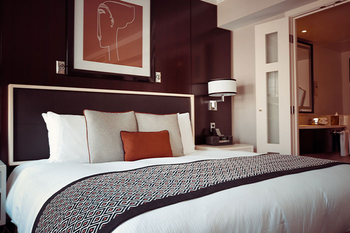 Modern bedroom with a neatly made bed, pillows, and a nightstand, symbolizing woman welcomes brother&rsquo;s family stay.