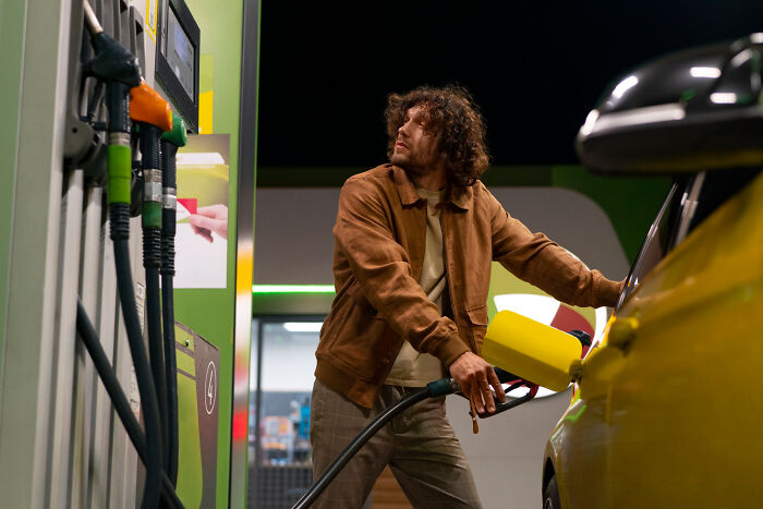 Man fueling car at gas station at night, illustrating small decisions leading to unexpected life-altering consequences.
