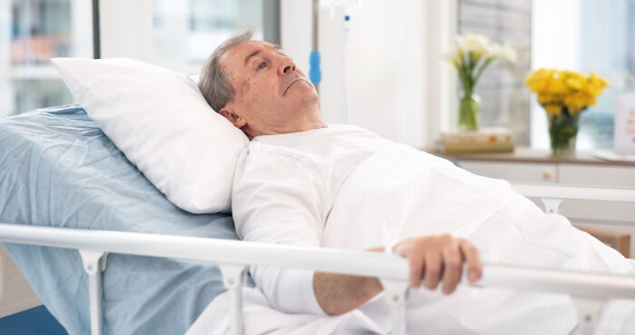 Elderly man lying in hospital bed reflecting on small decisions with unexpected life-altering consequences in a bright room.