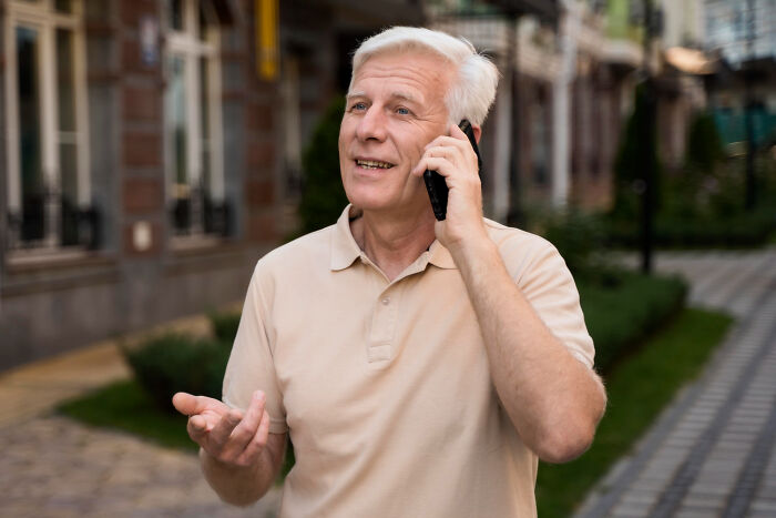 Older man in beige shirt making a phone call outdoors, illustrating stories of small decisions with unexpected life-altering consequences.