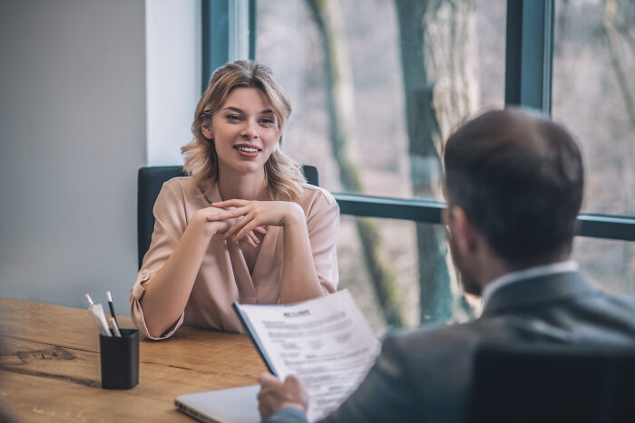 Young woman in a beige blouse during a job interview, illustrating stories of small decisions with life-altering consequences.