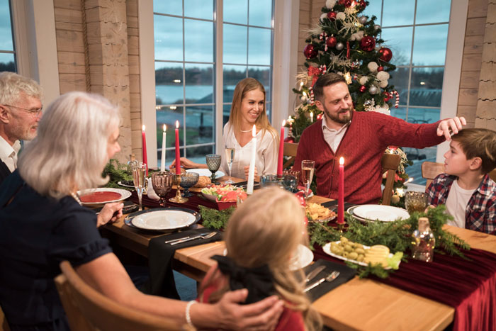 Family gathered around a festive Christmas dinner table, highlighting lazy relatives not bringing food to the meal.
