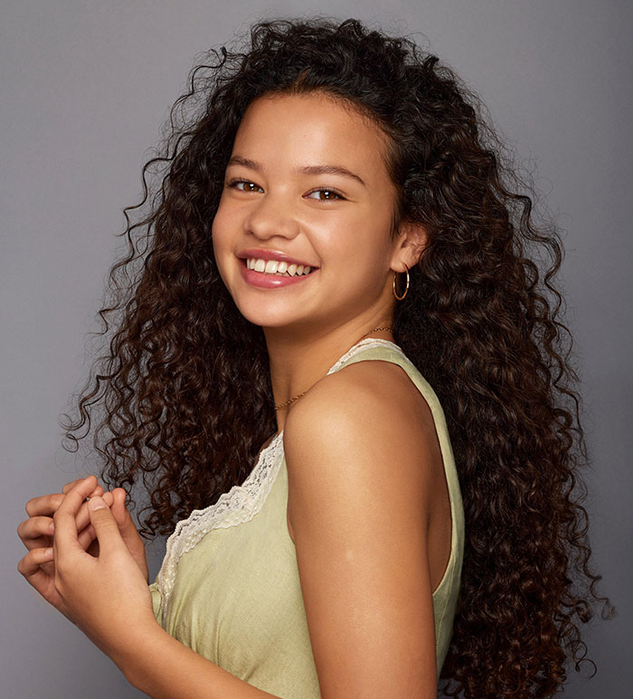 Young woman with curly hair smiling against a gray background, representing perspectives on what happened to Disney.
