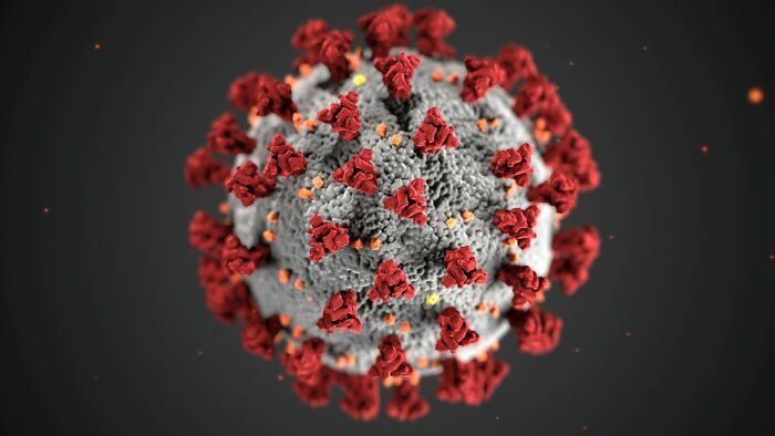 Close-up 3D illustration of a virus with red spike proteins, representing facts that sound made up but are true.
