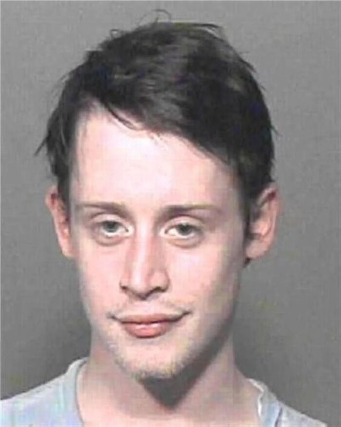 Young man with dark hair in a mugshot photo, representing celebs having their mugshot taken after being arrested.