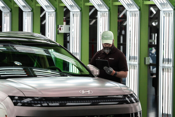 Worker inspecting a Hyundai vehicle in a factory setting, highlighting safety after forklift accident claims CEO's life.