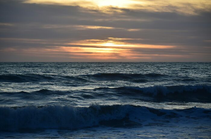 Sunset over a dark ocean with waves, illustrating the mysterious and disturbing science facts about nature's power.