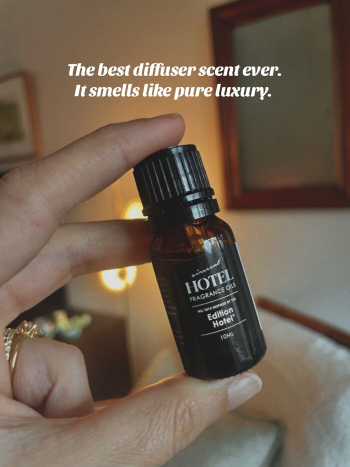 Hand holding a small bottle of hotel fragrance oil diffuser scent, a recommended Christmas gift idea.