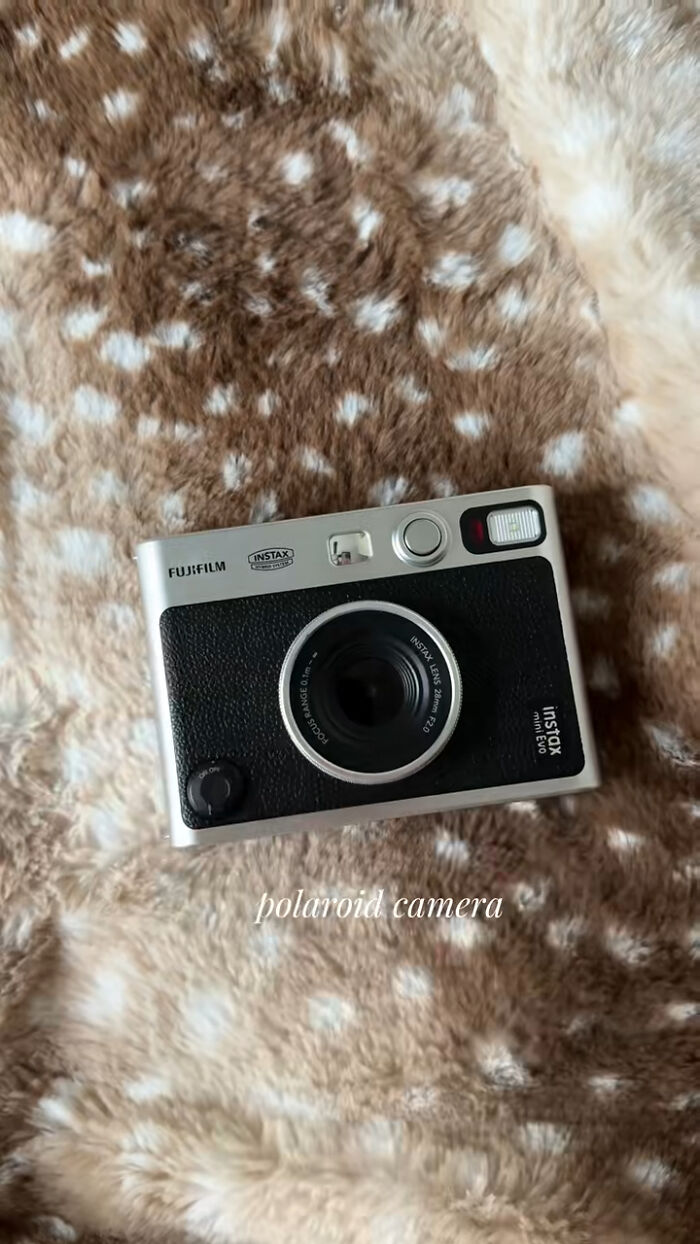 Fujifilm Instax Polaroid camera on soft brown and white spotted fuzzy blanket, popular Christmas gift idea.