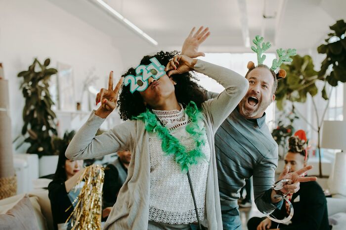 Two coworkers wearing festive accessories and having fun, showcasing wild work Christmas party moments.