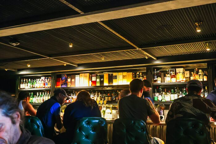 People sitting and chatting at a dimly lit bar during work Christmas parties leading to wildest stories ever.