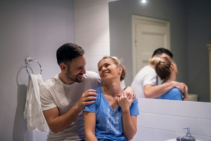 Couple sharing a joyful moment in bathroom, capturing a lighthearted scene from work Christmas party stories.