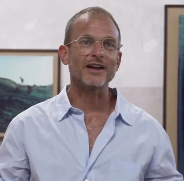 Man wearing glasses and a light blue shirt speaking indoors, related to VF photographer defending Karoline Leavitt close-up.