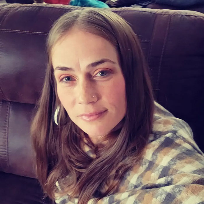 Woman with long brown hair and nose piercing sitting on a couch related to racist Cinnabon worker viral tirade news. Woman with long brown hair and nose piercing sitting on a couch related to racist Cinnabon worker viral tirade news.