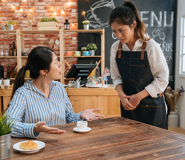 Customer angrily talking to cafe waitress, illustrating rude millennial women as new Gen Z social trend keyword. Customer angrily talking to cafe waitress, illustrating rude millennial women as new Gen Z social trend keyword.