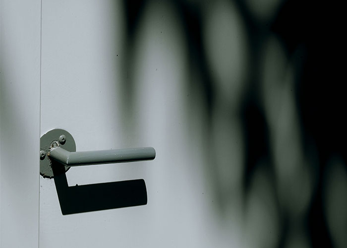 Close-up of a closet door handle casting a shadow, illustrating the topic of a guy venting online about closing the closet door.