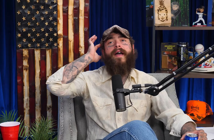 Bearded man with tattoos recording a podcast, sharing stories about running into different celebrities and reactions.